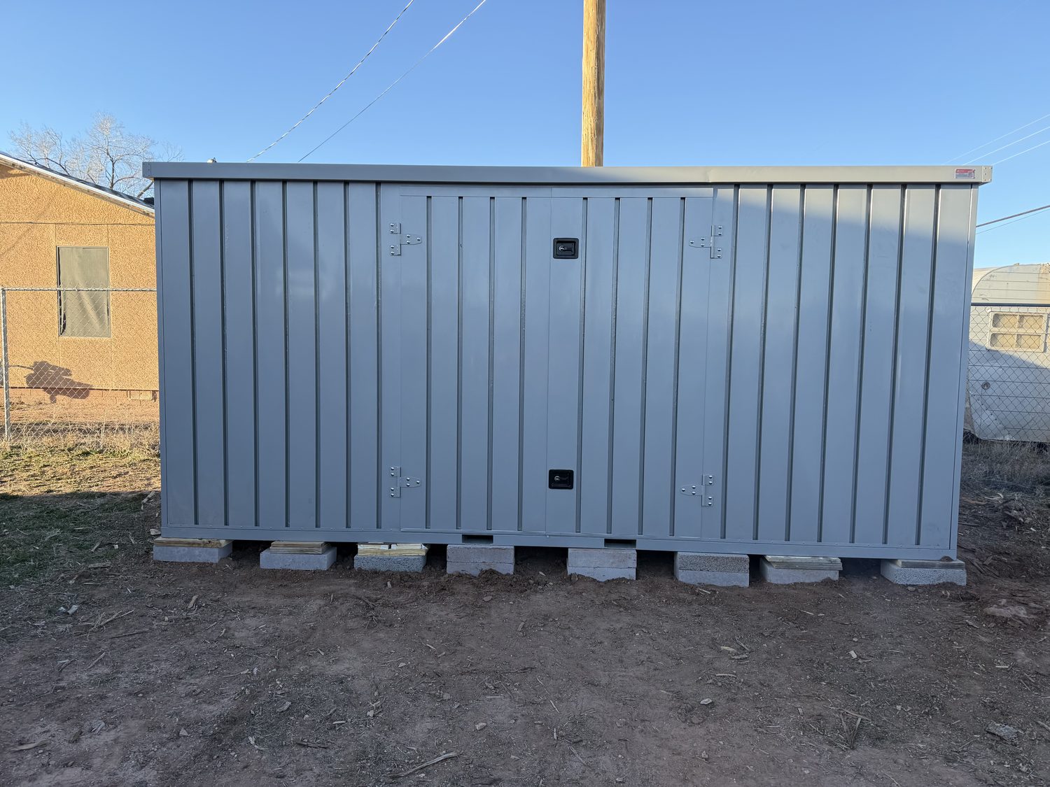 Grey My Yard Vault 4 Corners on a block-and-timber base in a residential lot